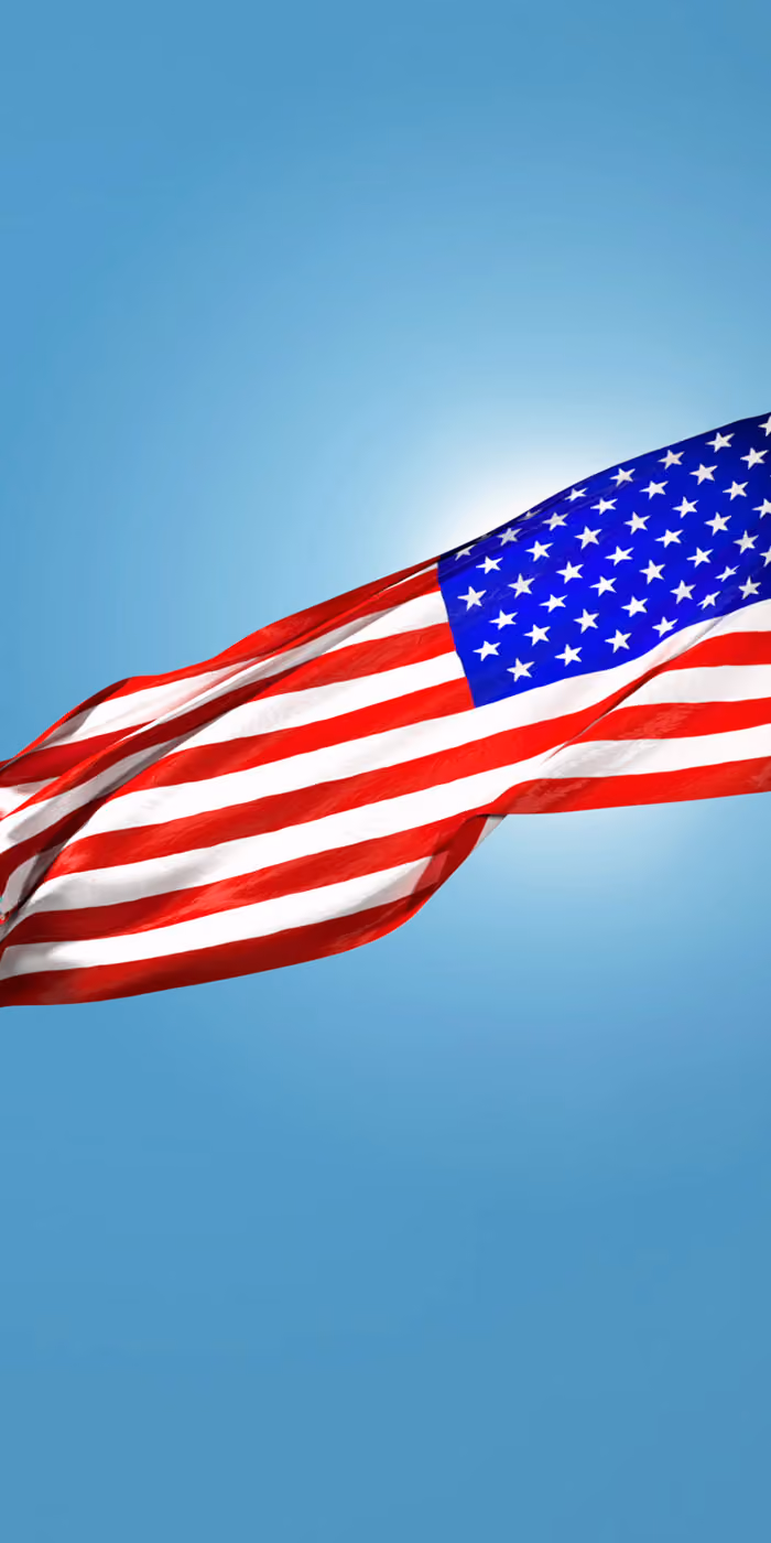 The USA flag waving against the blue sky.
