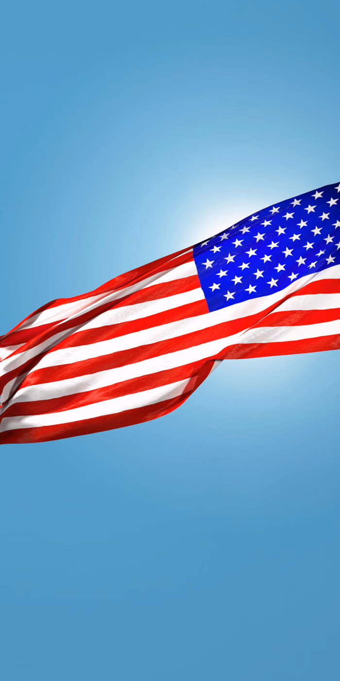 The USA flag waving against the blue sky.