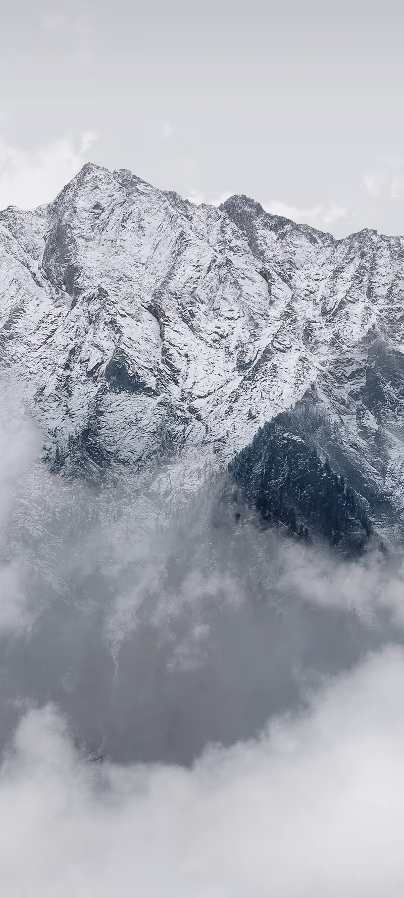 Clouds drift between mountain peaks in dense fog.