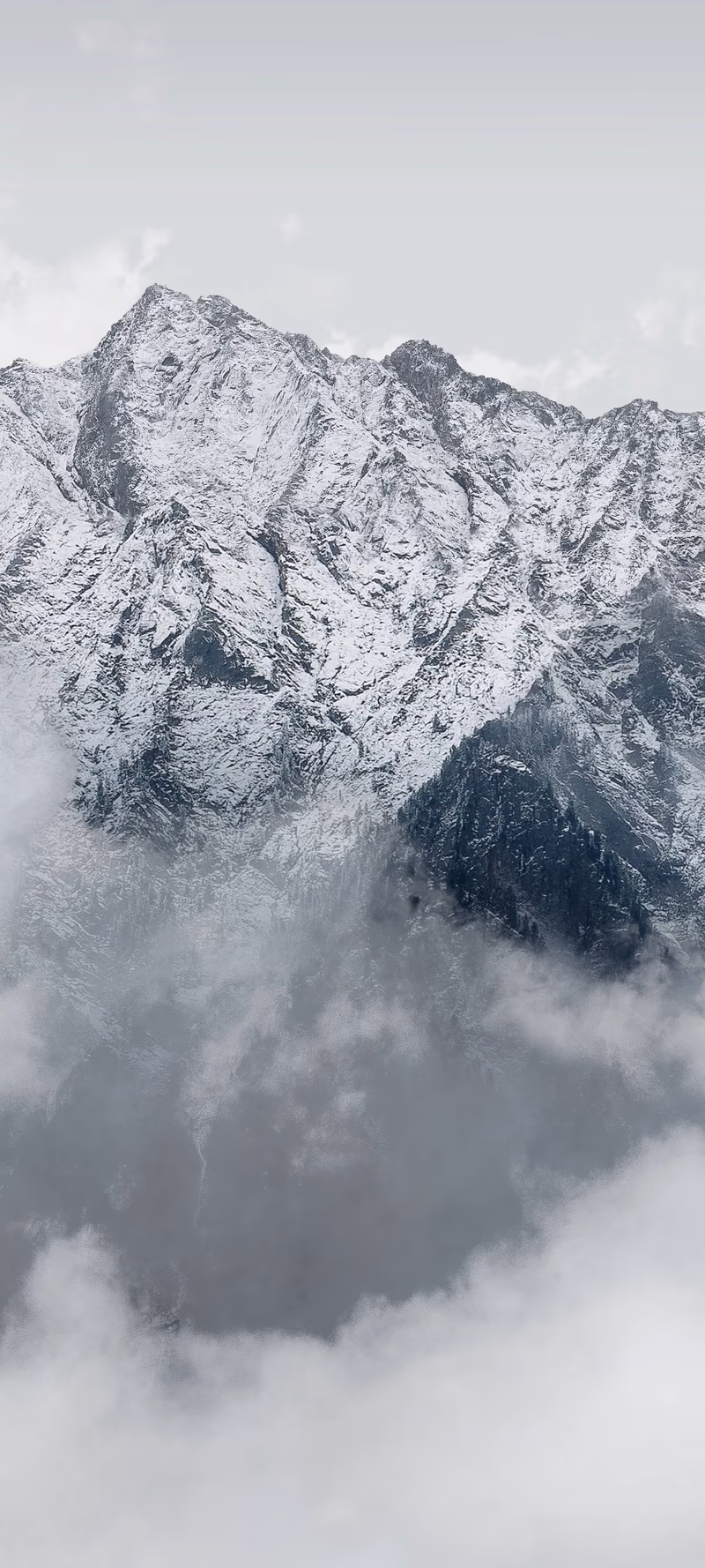 Clouds drift between mountain peaks in dense fog.