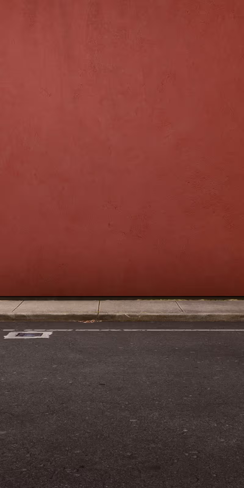 A plastic bag drifts beside a red wall.