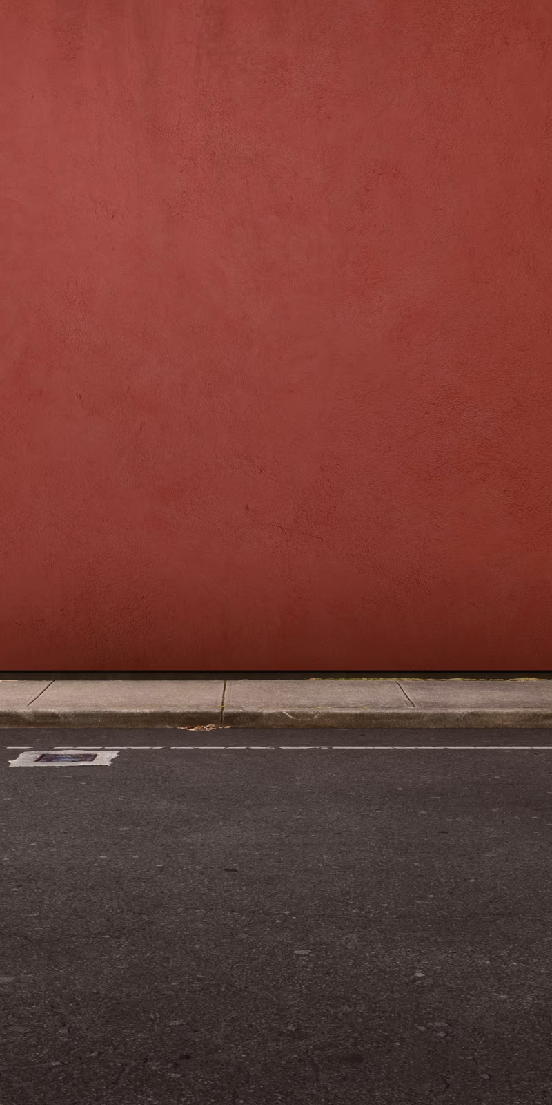 A plastic bag drifts beside a red wall.
