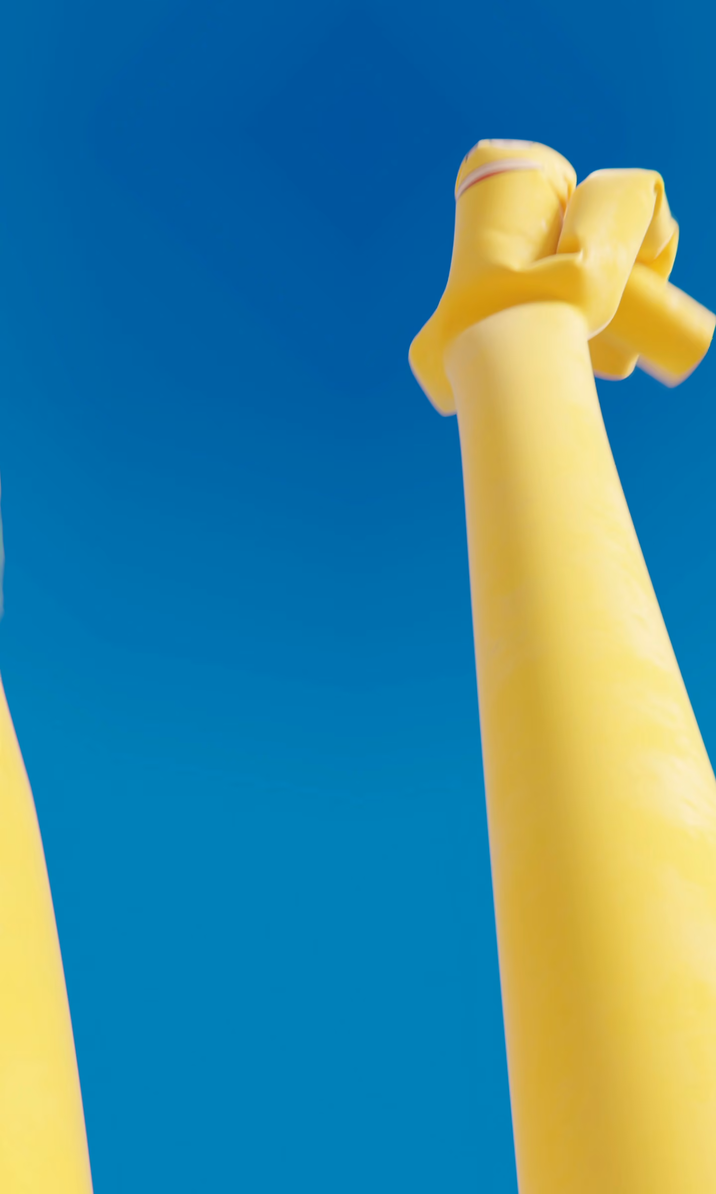 Two inflatable yellow skydancers sway against a bright blue sky.