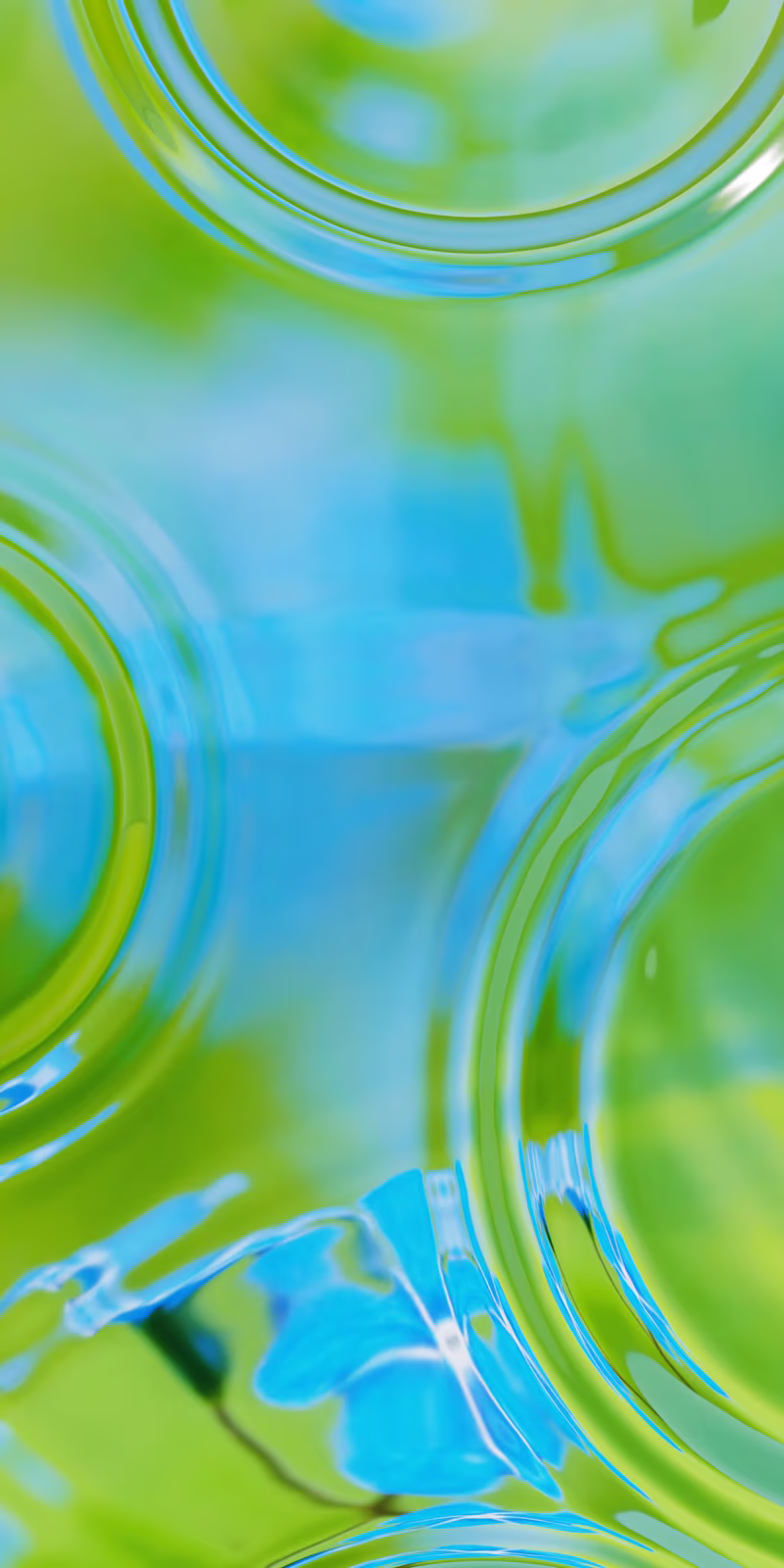 Ripples spread across water reflecting green and blue light.